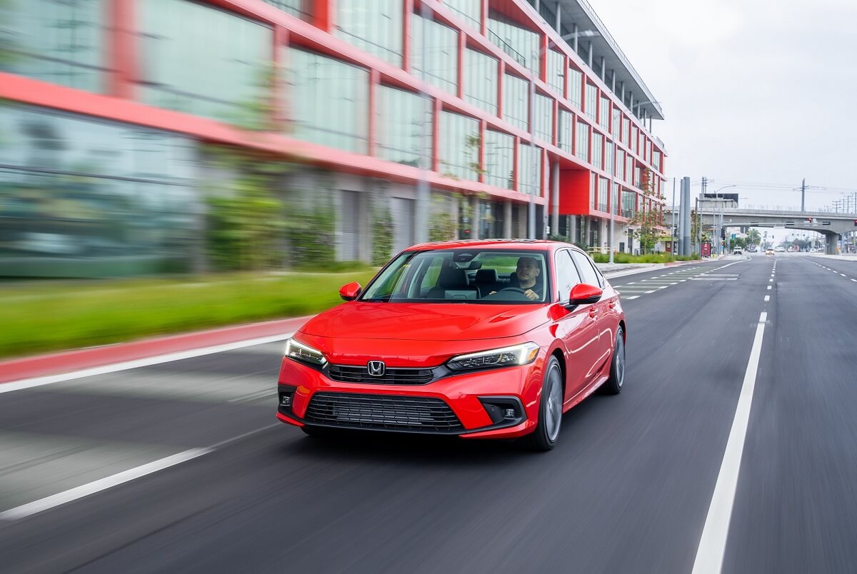 A small, red 2022 Honda Civic blasts down a safe city street away from other cars.