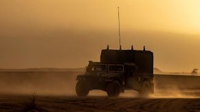 A surplus Humvee military vehicle drives through an African desert.