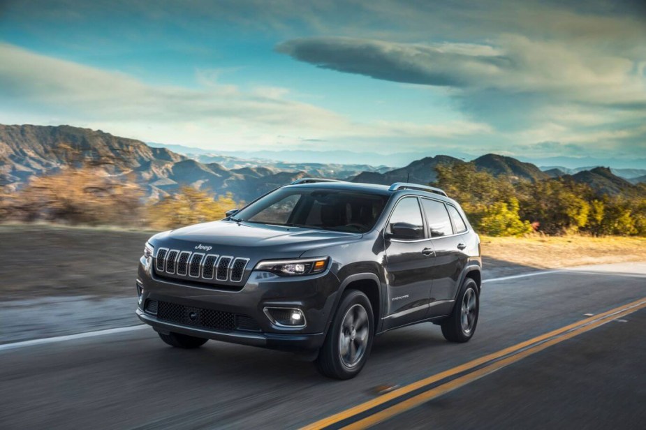 The 2023 Jeep Cherokee driving on the road by mountains and experiencing American freedom as an eagle caws.