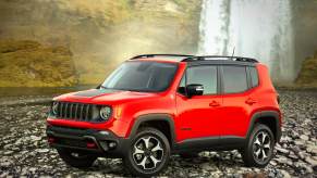 An orange 2022 Jeep Renegade in front of a waterfrall.