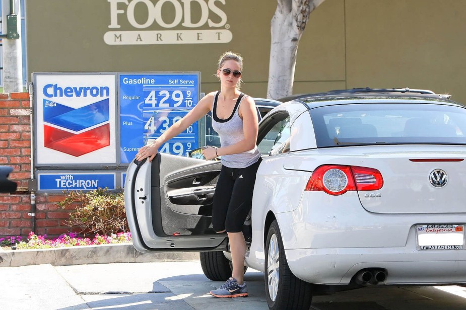 Actress Jennifer Lawrence getting out of her white, 2012 Volkswagen EOS, Whole Foods visible in the background.