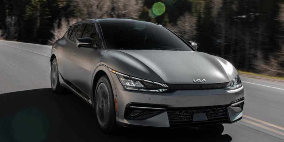 A gray 2023 Kia EV6 small electric SUV is driving on the road.