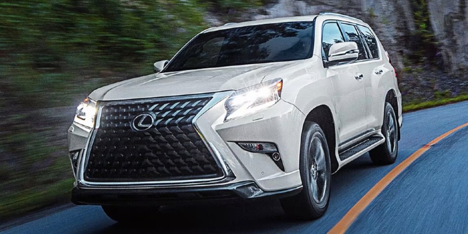 A white 2023 Lexus GX full-size SUV is driving on the road.