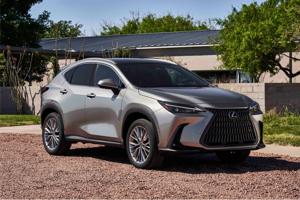 A silver Lexus NX hybrid sits in front of a house surrounded by trees.