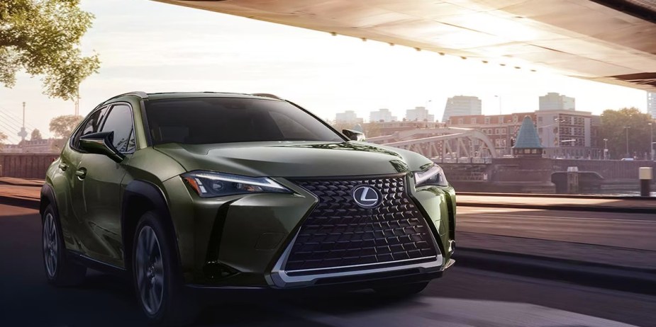 A green 2023 Lexus UX Hybrid subcompact hybrid SUV is driving on the road. 