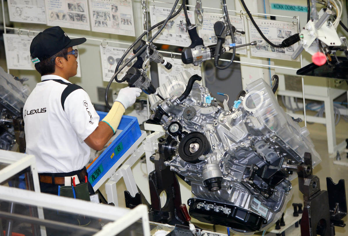 A Lexus factory worker works on a Lexus V8 engine