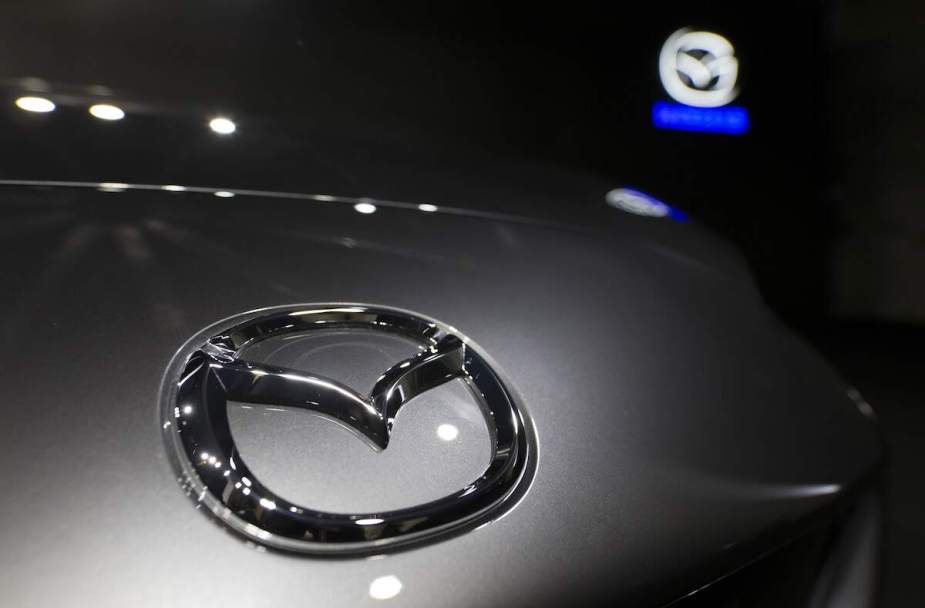 A Mazda logo on a Mazda MX-5, one of the top Mazda models, with a blurred Mazda logo in the background.