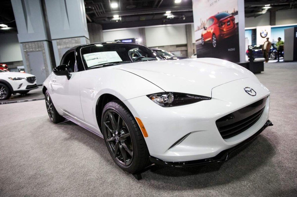 A white Mazda Miata parked indoors, which you may possibly get a Mazda Miata Speedster Kit for. 