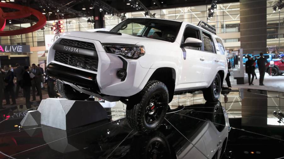 A new Toyota 4Runner in white propping up one wheel on a black floor at an auto show.