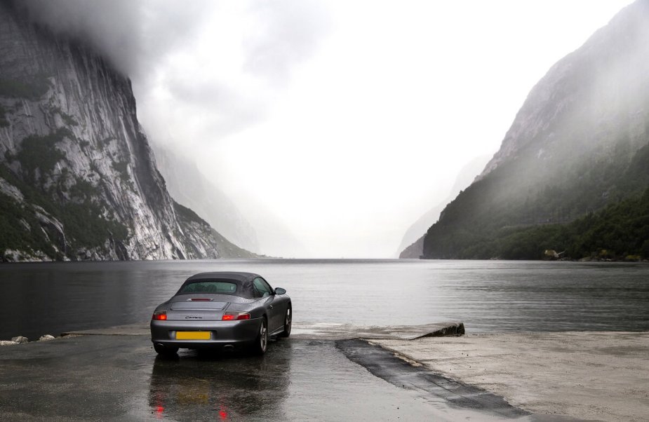 A used silver 996 Porsche 911 Convertible poses at a Norwegian Fjord. 