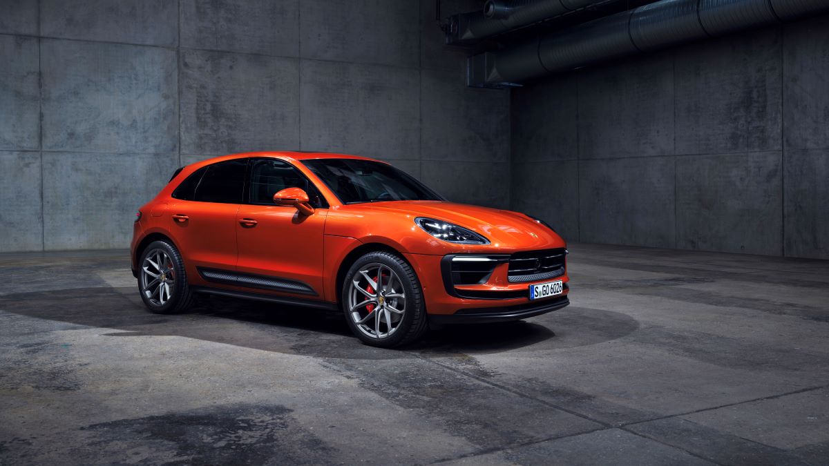 An orange Porsche Macan S high-performance luxury compact SUV model in a concrete room