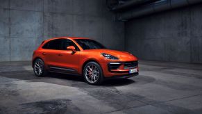 An orange Porsche Macan S high-performance luxury compact SUV model in a concrete room