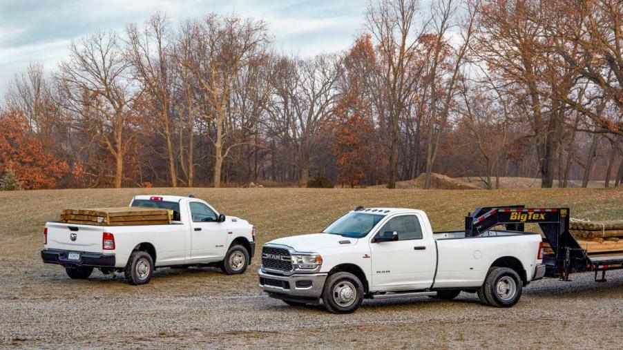 A pair of white Ram 2500 and 3500 heavy-duty (HD) Tradesman models working in a forest plain