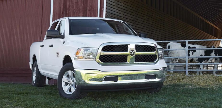 A white Ram Classic full-size truck sits by a barn.
