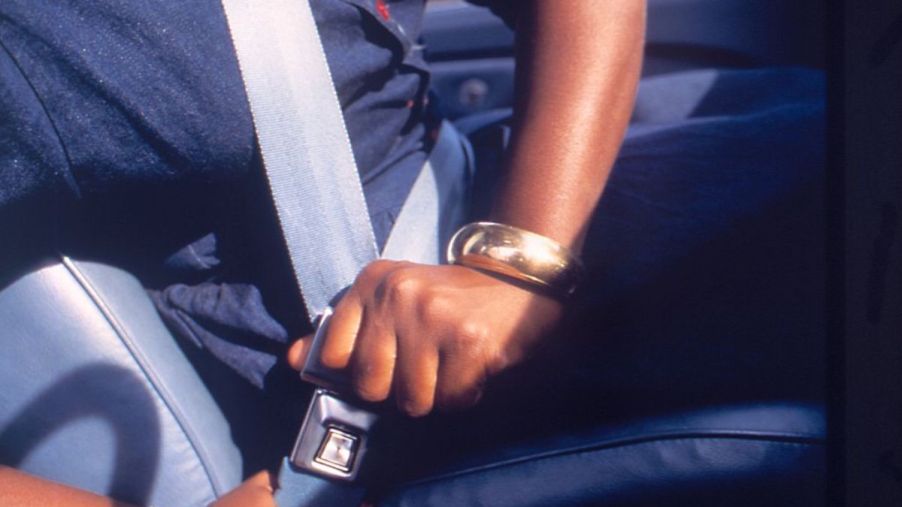 A person in a car buckling their seat belt.