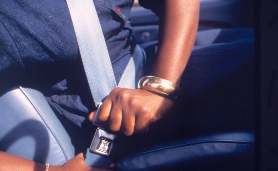 A person in a car buckling their seat belt.
