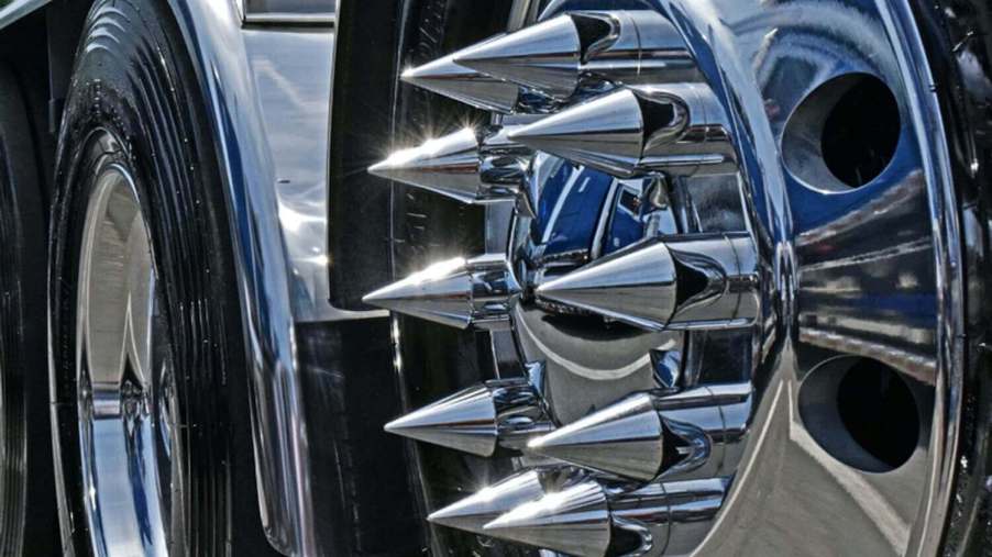 Closeup of the chromed lug nut cover spikes on the wheel of a semi truck.