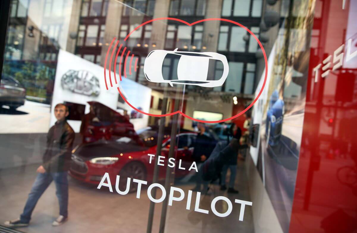 A logo/icon of the Tesla Autopilot function on a glass window of a dealership showroom in London, United Kingdom