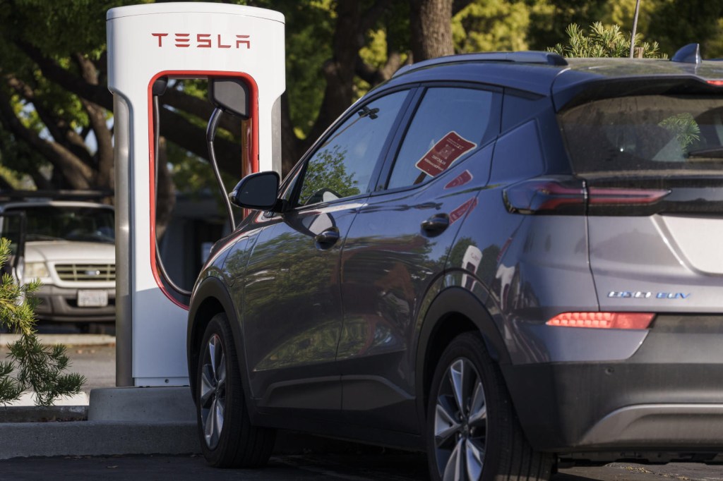 A Chevy Bolt electric vehicle parked at a Tesla Supercharger utilizing the Tesla Magic Dock