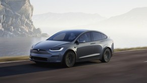 A gray 2023 Tesla Model Y small electric SUV is driving.