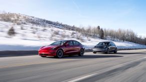 A red Tesla Model 3 and Model Y, the cheapest cars in the lineup, blast down a winter road.