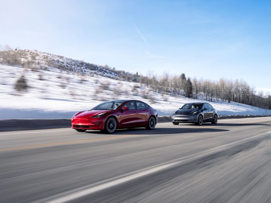 A red Tesla Model 3 and Model Y, the cheapest cars in the lineup, blast down a winter road. 
