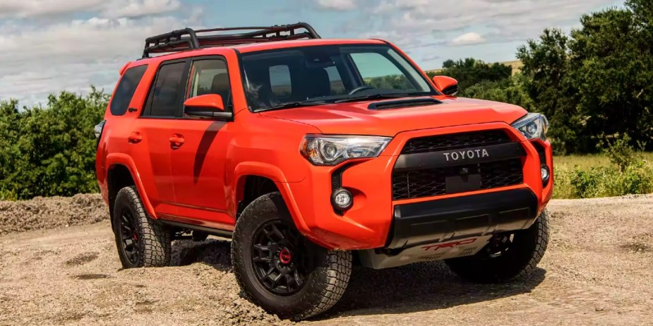 An orange Toyota 4Runner midsize SUV is parked off-road.