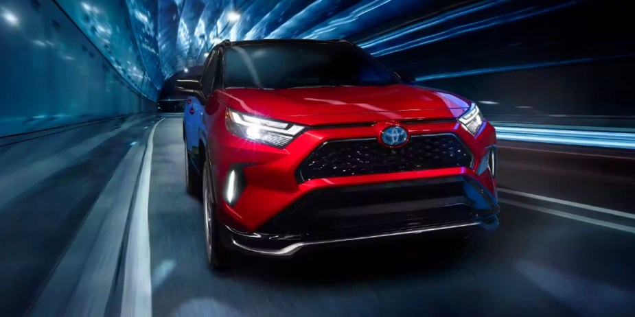 A red Toyota RAV4 Prime small plug-in hybrid SUV is driving. 