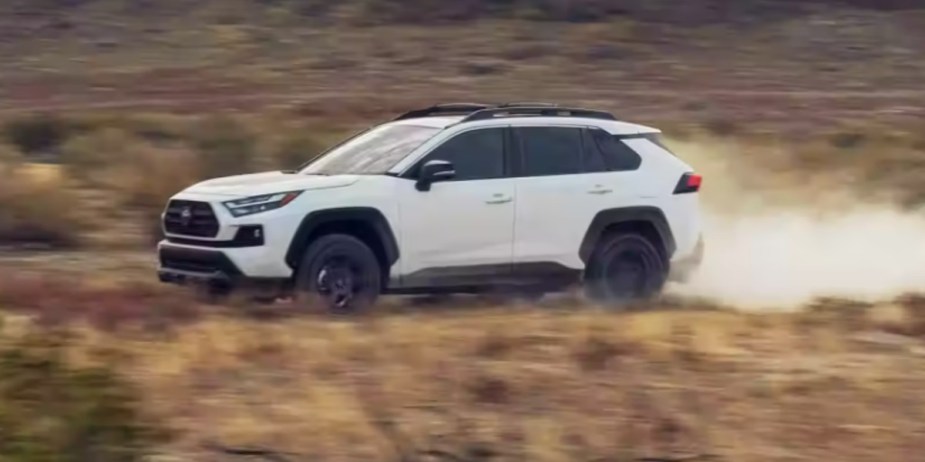 A white 2023 Toyota RAV4 small SUV is driving off-road. 
