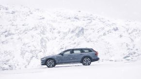 A 2023 Volvo V90 Cross Country in Thunder Grey driving near snowy mountains