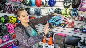 A bike shop employee showing off bike helmet features to a customer in Bogota, Colombia, Engativa