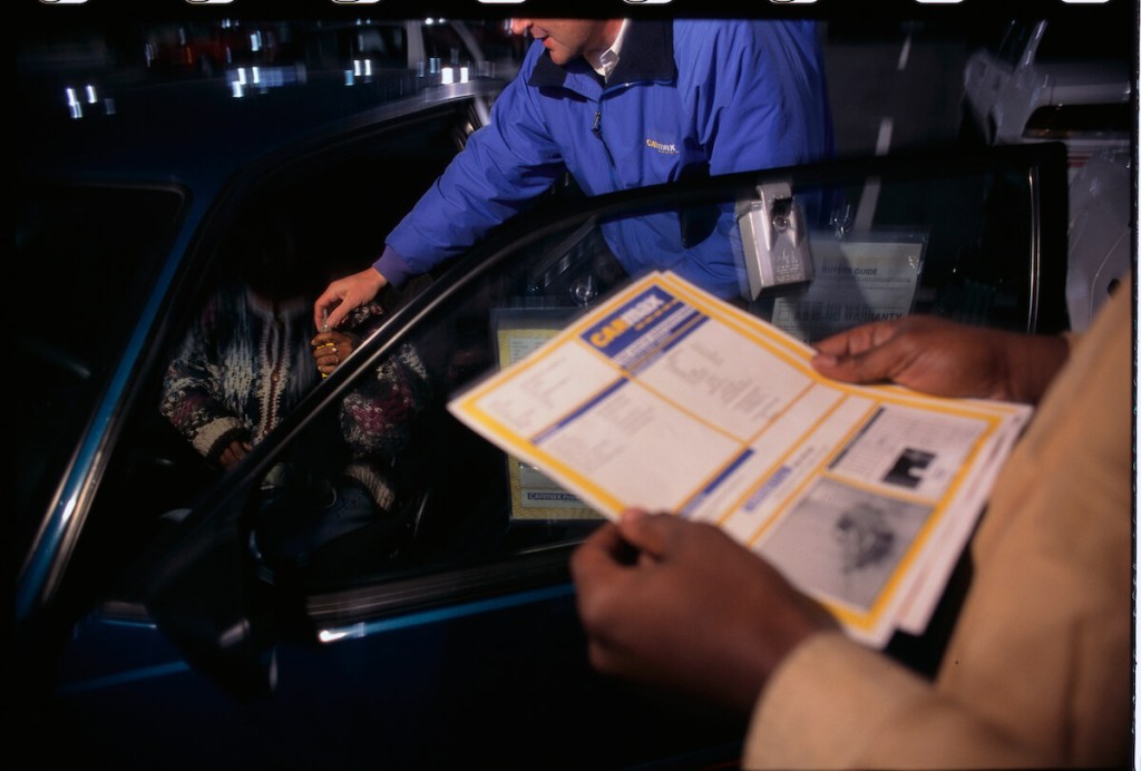 A Carmax sales person gives a customer an offer.