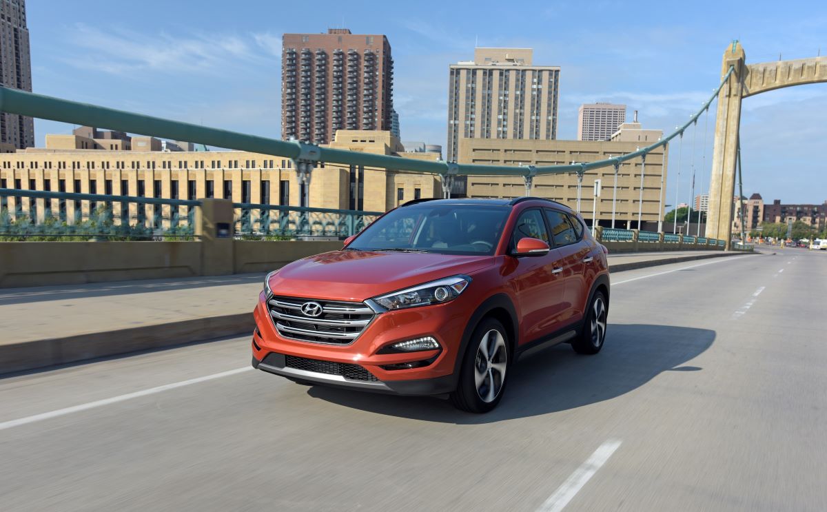 A red-range 2018 Hyundai Tucson compact crossover SUV model crossing a bridge