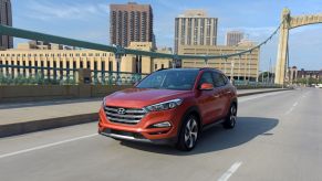 A red-range 2018 Hyundai Tucson compact crossover SUV model crossing a bridge