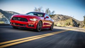 A red 2015 Ford Mustang muscle car coupe model speeding down a highway