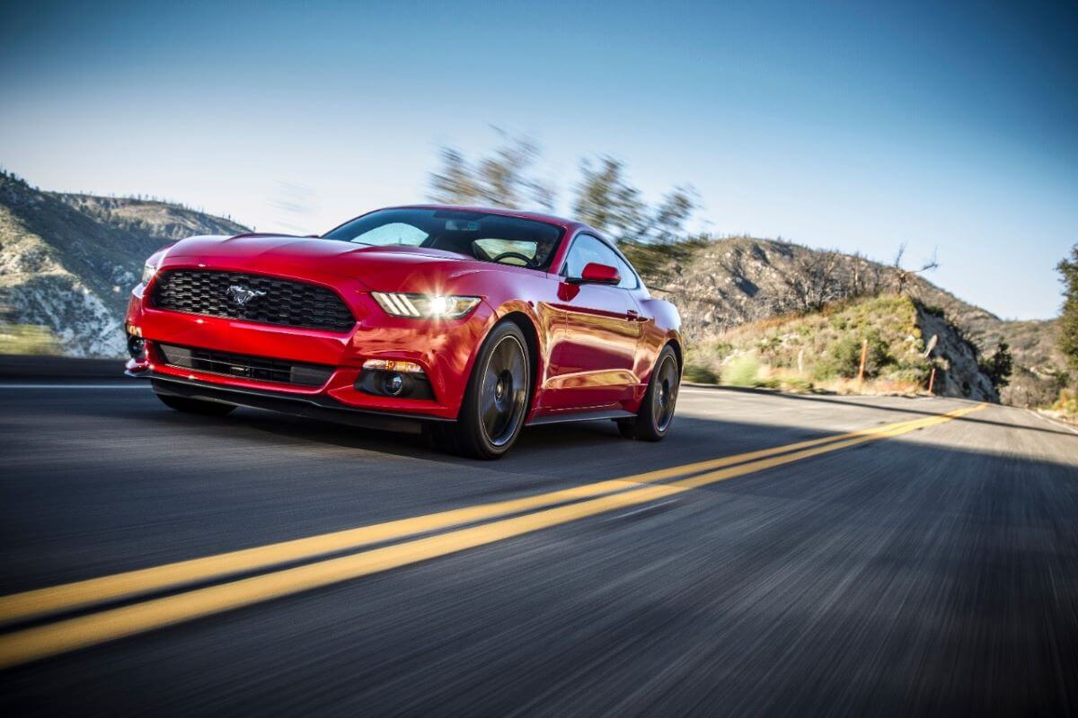 A red 2015 Ford Mustang muscle car coupe model speeding down a highway