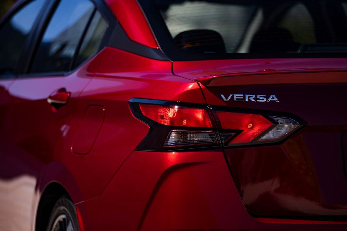 A red 2023 Nissan Versa subcompact sedan model rear exterior styling and model badging