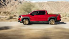 A side profile shot of a red 2023 Honda Ridgeline Sport with HPD Package midsize pickup truck on a desert road