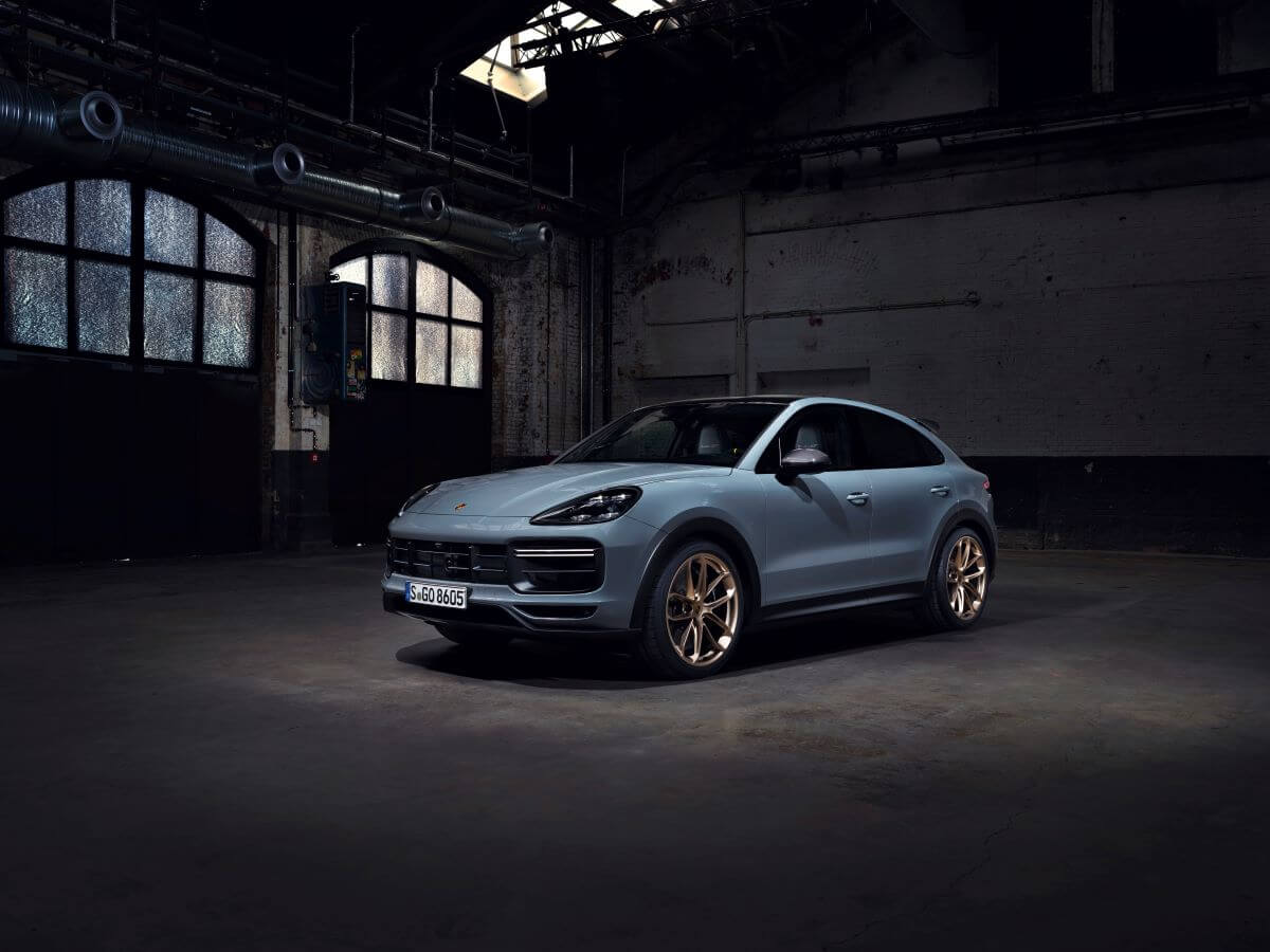 A steel blue Porsche Cayenne Turbo GT midsize luxury crossover SUV model parked in an empty warehouse garage