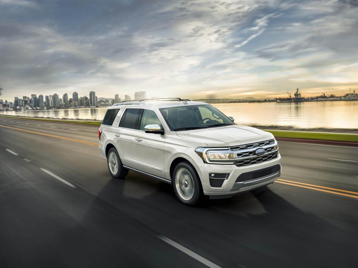 A white 2023 Ford Expedition full-size SUV model driving on a highway near water
