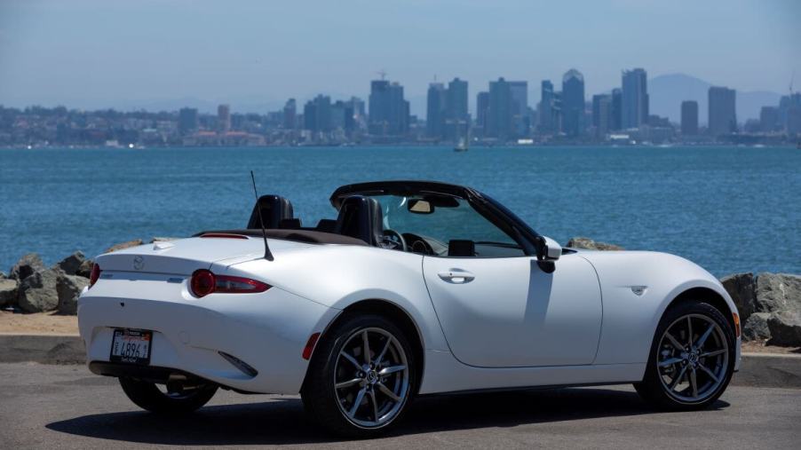 A white 2019 Mazda MX-5 Miata convertible coupe sports car model parked near a large body of water