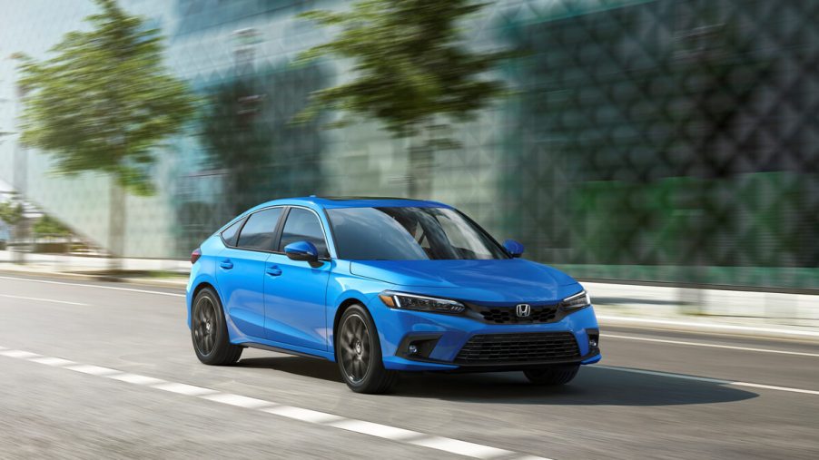 A bright blue 2022 or 2023 Honda Civic LX Hatchback sports a handsome facelift on city streets.