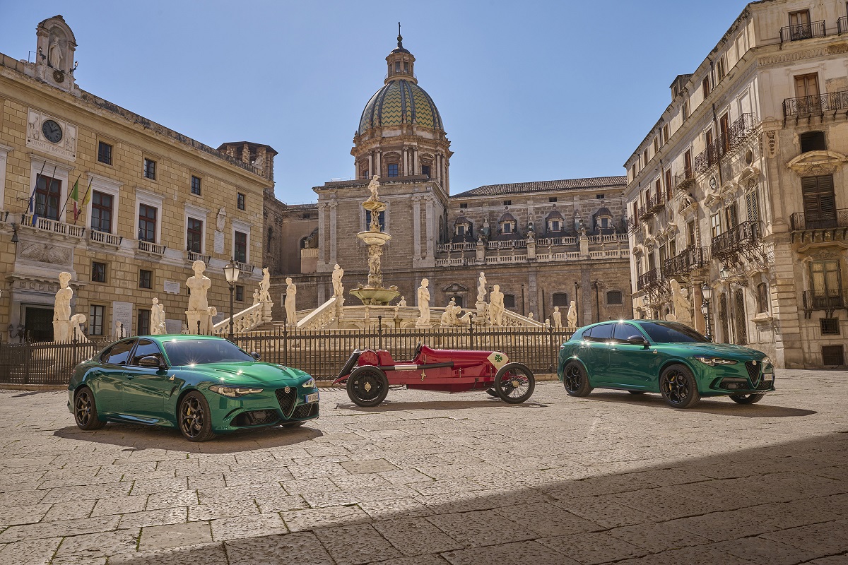 A green Alfa Romeo Giulia and Stelvio flanking a 123 Quadrifoglio race car.