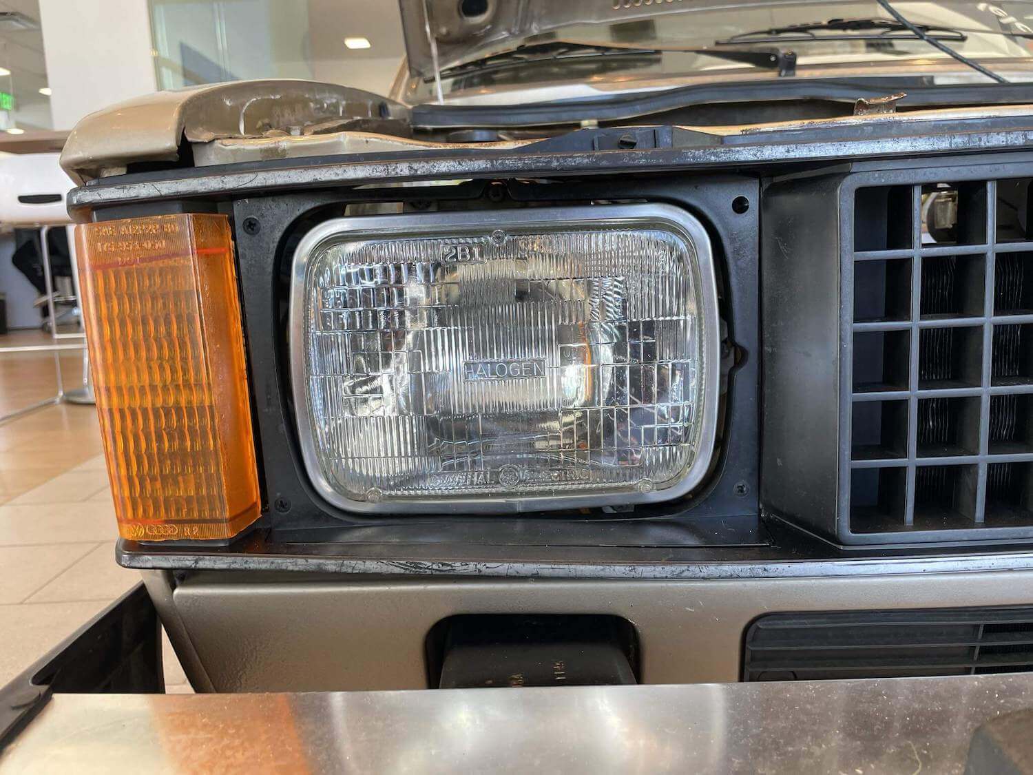 Closeup of the square headlight, grille, and turn signal of a Volkswagen Rabbit compact pickup truck.
