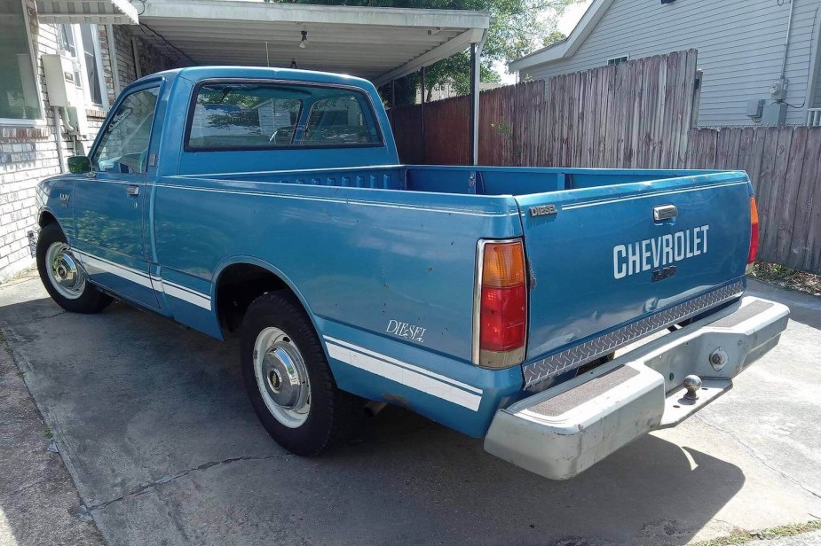 The pickup bed of a 1982 Chevy LUV compact diesel truck, parked in front of a home.