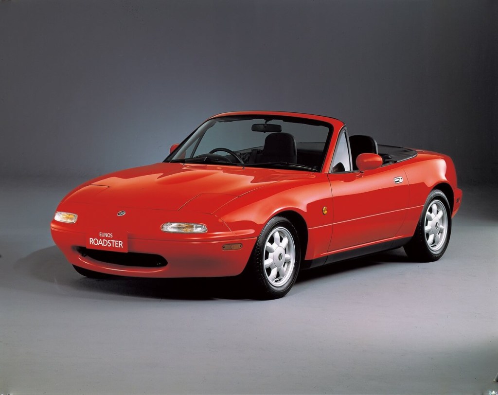 A red Mazda MX-5 Miata sports car poses on a stage. 