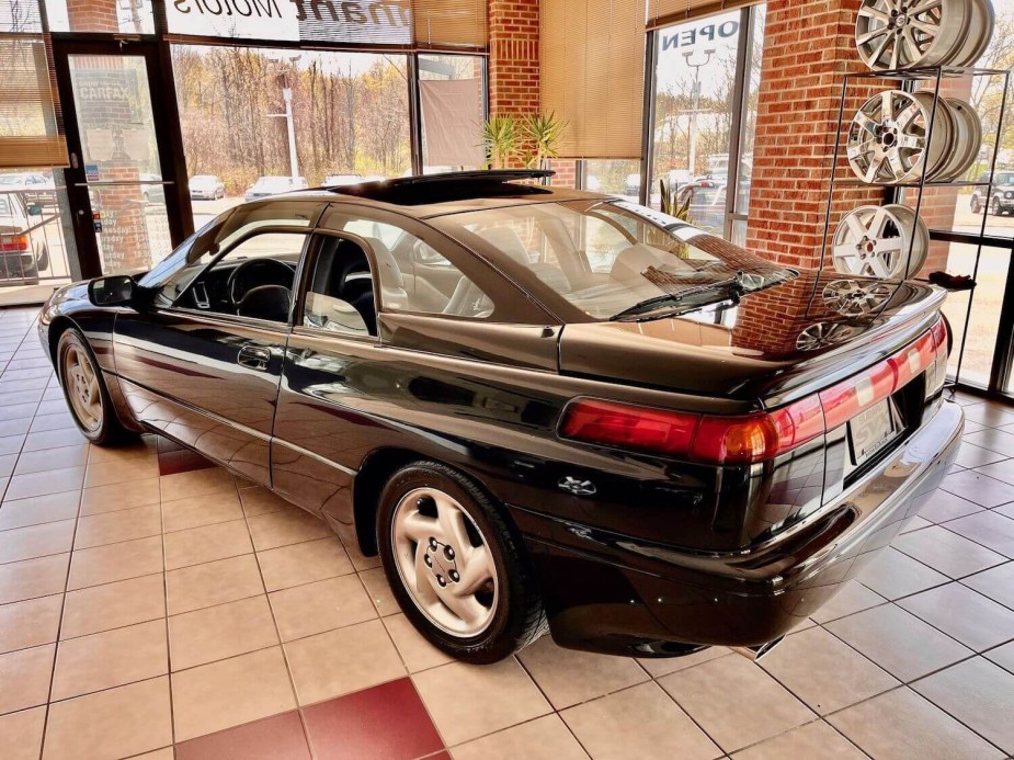 A black subaru SVX coupe is parked in a used sports car dealership showroom.