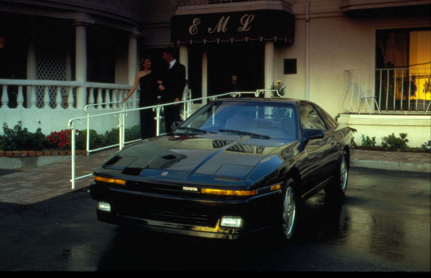 A black 1987 supra parked at a restaurant