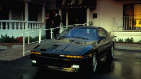 A black 1987 supra parked at a restaurant