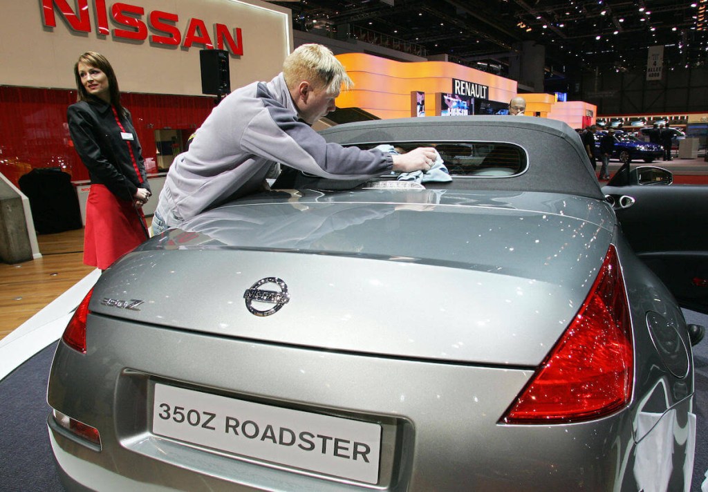 A man wipes down a Nissan 350Z roadster at an auto show.